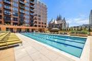 Stamford apartment for rent - A large swimming pool with lounge chairs is surrounded by a building.