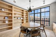 Stamford apartment for rent - A dining room with a round table and chairs, a shelf with decorative items, and a view of the city through large windows.