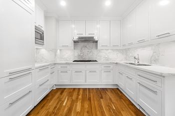 A white kitchen with white cabinets and a wood floor
