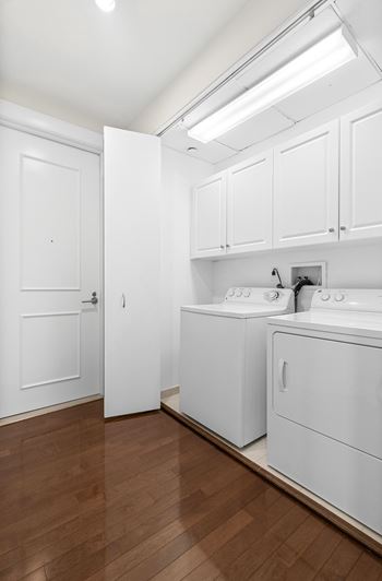 A washer and dryer in a room with white cabinets and a wood floor