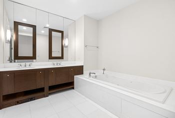 A large white bathroom with a tub and two sinks