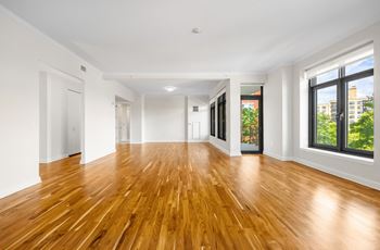 A living room with a hard wood floor and large windows