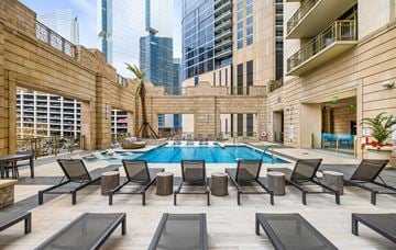 Houston apartment for rent - A pool surrounded by lounge chairs in a courtyard.