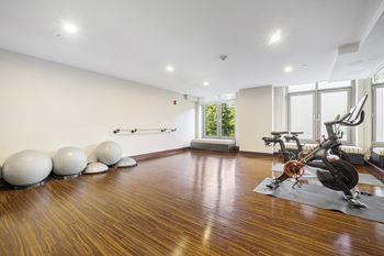 A gym with weights and yoga balls on the floor and a window