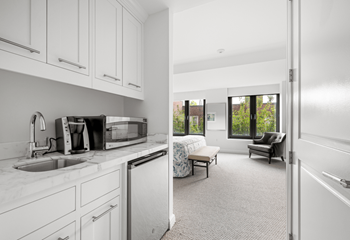 A kitchen with white cabinets and a sink and a window