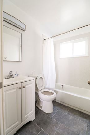 Oakland apartment for rent - A white toilet is in a bathroom with a white cabinet and a window.