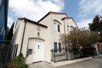 Oakland apartment for rent - A white house with a black fence in front.
