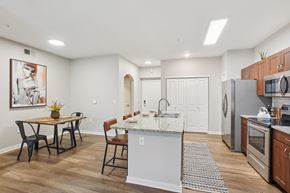 Denver apartment for rent - A kitchen with a table and chairs in the foreground and a refrigerator, microwave, and oven in the background.
