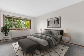 New Hope apartment for rent - A bedroom with a large bed and a window overlooking a green tree.