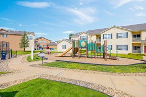 Rochester townhouse for rent - A playground with a slide and swings in front of apartment buildings.