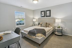 Lincoln apartment for rent - A bedroom with a bed, nightstand, and chair at The Donovan Apartment Homes, Nebraska
