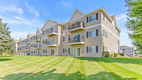 Isanti apartment for rent - a large apartment building with balconies and a lawn