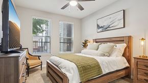 Denver apartment for rent - A bedroom with a bed, chair, and a television.