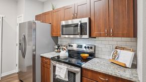 Denver apartment for rent - A kitchen with a refrigerator, microwave, oven, and a stove top.