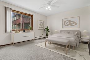 Plymouth apartment for rent - A bedroom with a large bed, a dresser, and a ceiling fan.