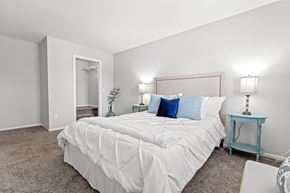 Lakeville townhouse for rent - A bedroom with a large bed and a small table with a lamp.