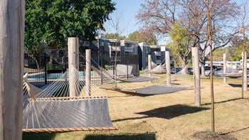 A playground with hammocks and a fence and houses in the background
