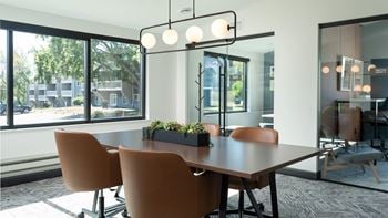 A conference room with a large window and a table with chairs
