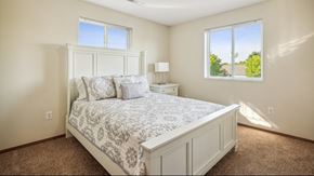 Grand Forks apartment for rent - A bedroom with a large bed and a window overlooking a green landscape.