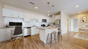 Denver apartment for rent - Spacious modern kitchen with white cabinetry, stainless steel appliances, and pendant lighting above the island. Kitchen opens up into separate dining area.