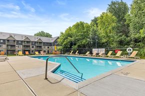 Rochester apartment for rent - A large swimming pool with a diving board and lounge chairs.