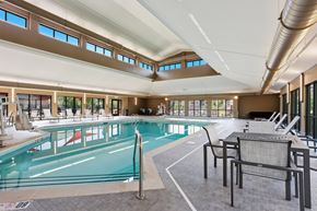 Grand Forks apartment for rent - A large indoor swimming pool with lounge chairs and a metal pole.