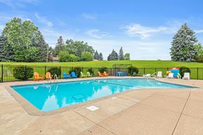 Roseville apartment for rent - A large outdoor swimming pool surrounded by a fence and lounge chairs.