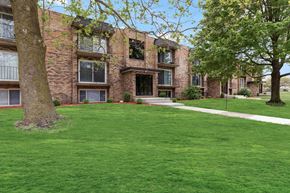 Matteson apartment for rent - exterior view of a brick apartment building with green grass and trees