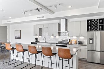 A modern kitchen with a bar area and chairs.