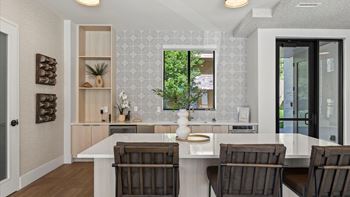 A kitchen with a white counter and brown chairs.