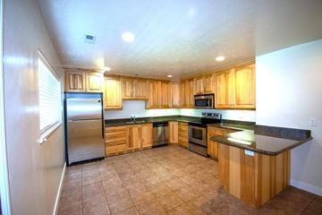 Provo apartment for rent - A kitchen with wooden cabinets and a black countertop.