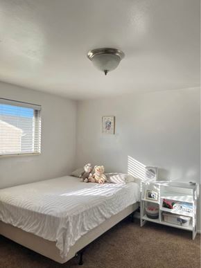 Orem apartment for rent - A white bedroom with a bed, nightstand, and a window with blinds.