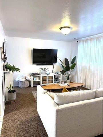Orem apartment for rent - A living room with a white couch and a flat screen TV mounted on the wall.