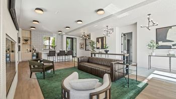 A modern living room with a green rug and a brown leather sofa.