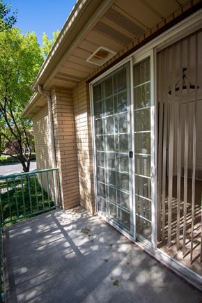 Provo apartment for rent - A glass door with a metal handle is on the right side of a brick building.