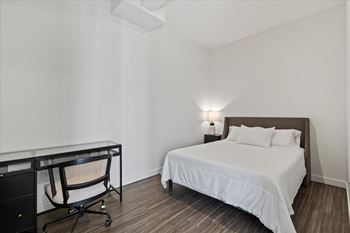 A bedroom with a bed, desk, and chair.