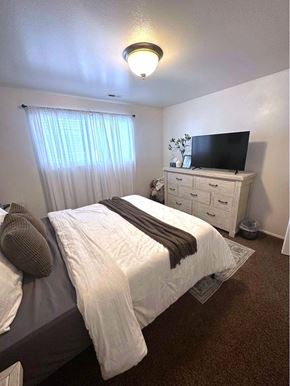 Orem apartment for rent - A bedroom with a bed, a dresser, and a television.
