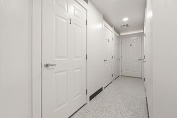 A hallway with white doors and a black baseboard.