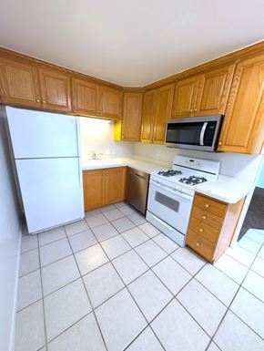 Provo apartment for rent - A kitchen with wooden cabinets and white appliances.