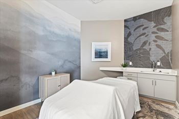 A bedroom with a white bed and a grey wallpapered wall.