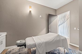 A room with a bed covered in a white sheet and a small ottoman.