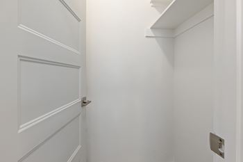 A white door with a silver handle is in a white room.