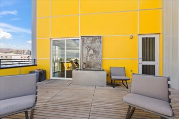 A yellow building with a glass door and two grey couches on the patio.