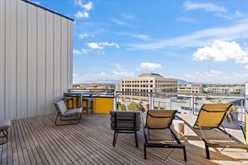 A balcony with chairs and a table overlooking a cityscape.