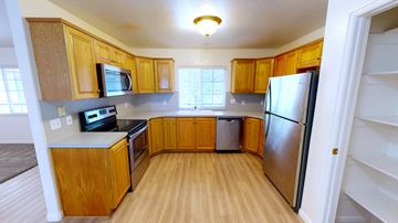 Orem apartment for rent - A kitchen with wooden cabinets and a refrigerator.