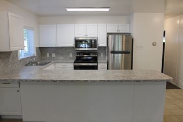 Provo apartment for rent - A kitchen with white cabinets and a granite countertop.