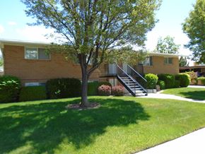 Orem apartment for rent - A tree in a grassy area in front of a building.