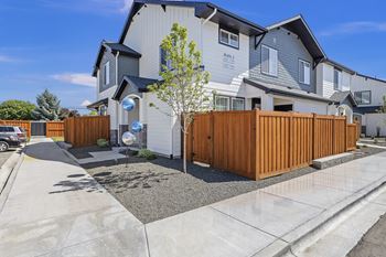 A modern house with a grey and white exterior and a brown fence.