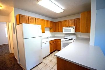 Provo apartment for rent - A white refrigerator is in a kitchen with brown cabinets.