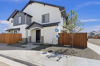 A modern house with a grey and white exterior and a wooden fence.